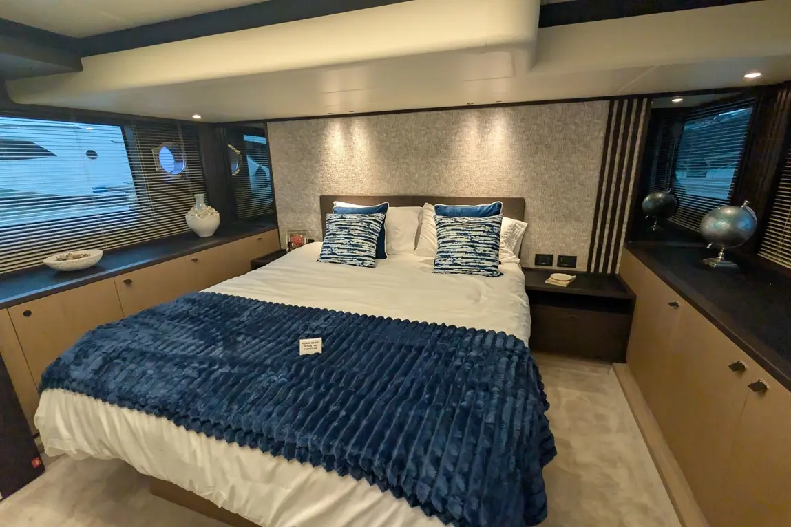 Luxurious bedroom featuring a plush bed with blue cushions, textured blanket, and stylish decor. Elegant maritime atmosphere.